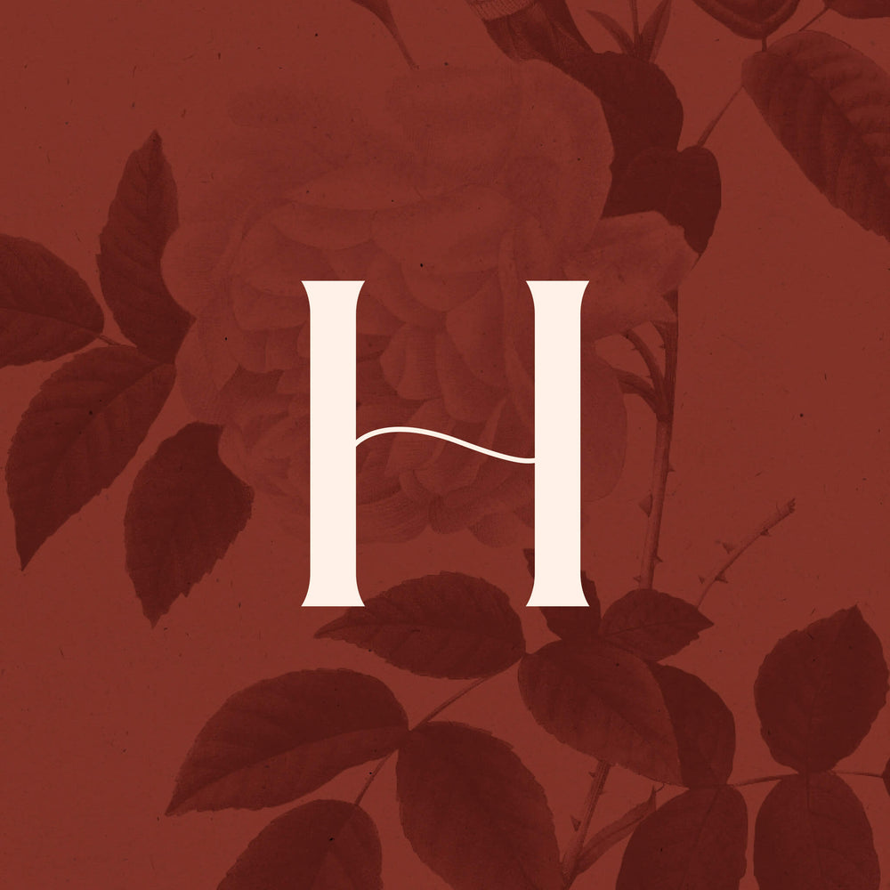 Fashion designer rebranding case study image of the Helena Rose icon. A cream ‘H’ with a curved crossbar sits over a rich red background with rose patterns subtle embellishing.