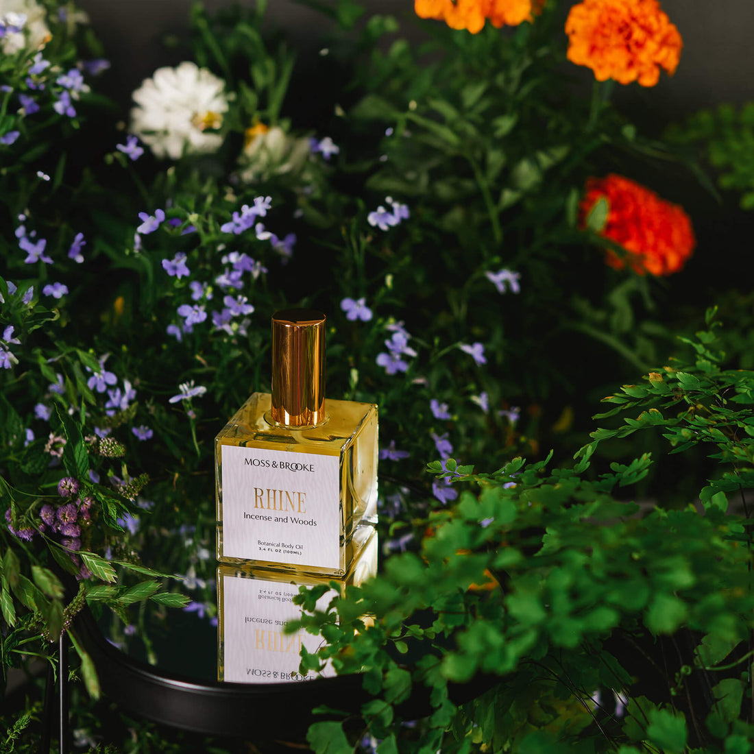 Perfume brand design example image of the Moss & Brooke perfume packaging design. In a heavy square glass bottle with a gold lid, the perfume has a cream coloured label with gold foil detailing.