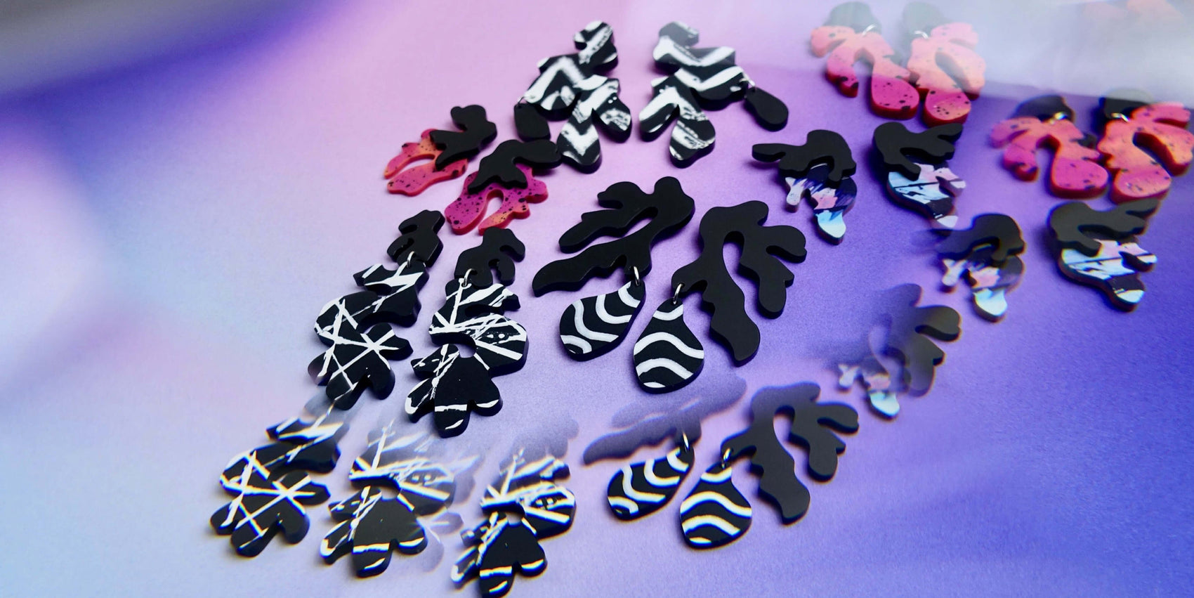 A jewellery brand design portfolio image of the Edenki products sitting on the brand gradient. A reflecting filter has been applied to create a mystical feel to the earrings.