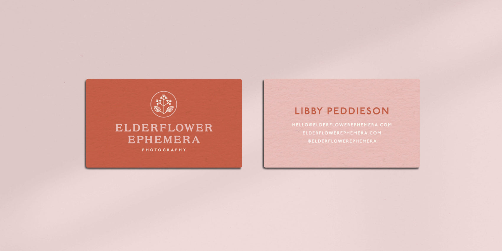 Brand design portfolio image of the Elderflower Epherma business cards. The front card features a rust colour background and pink and white logo while the back is pink with rust and white detailing. 