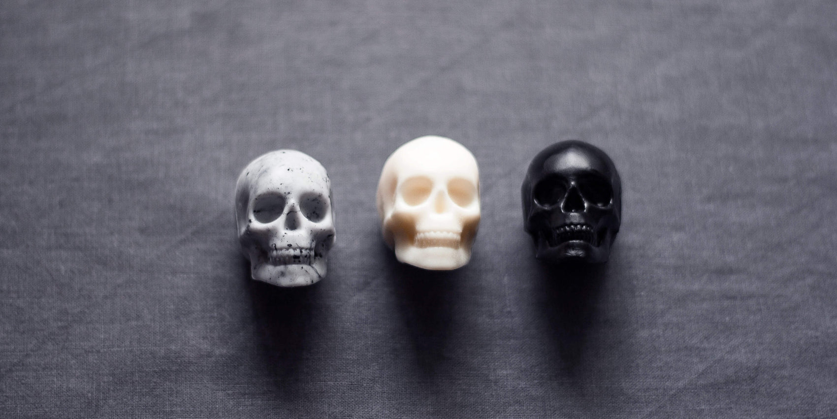 Soap brand identity examples image of Jingle Hells soap product. On a grey background sit three skull-shaped souls in marbled grey, white and black.