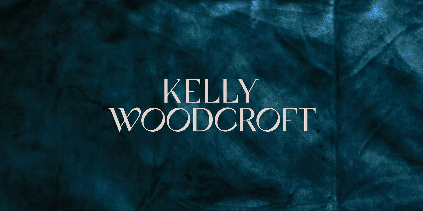 The custom jewellery designer logo for Kelly Woodcroft is in white on a shadowy teal velvet background. The elegant typography feels high end but still with personality.