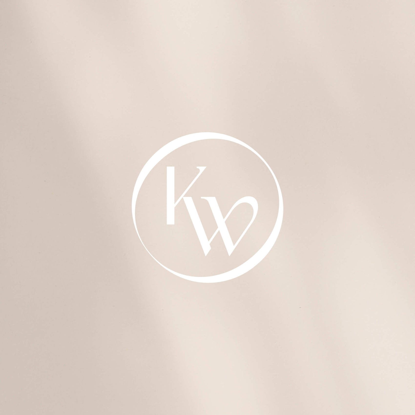 Fashion brand identity case study image of the Kelly Woodcroft interconnected brand seal. The white logo appears here on a cream coloured background. 