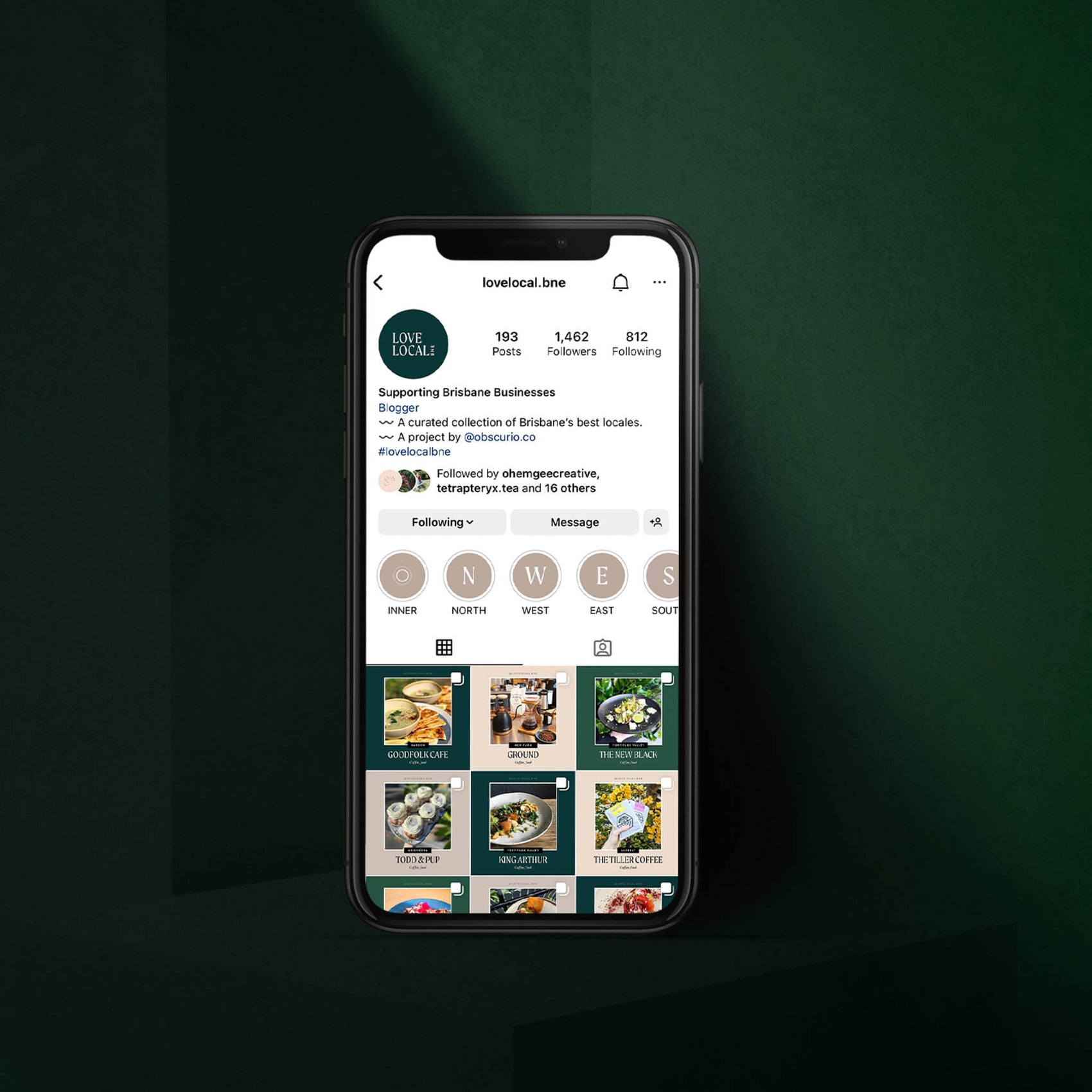 Brisbane brand design portfolio image of an iphone in a deep green background. The screen displays the Love Local BNE Instagram feed, showcasing posts of favourite destinations during lockdown. 