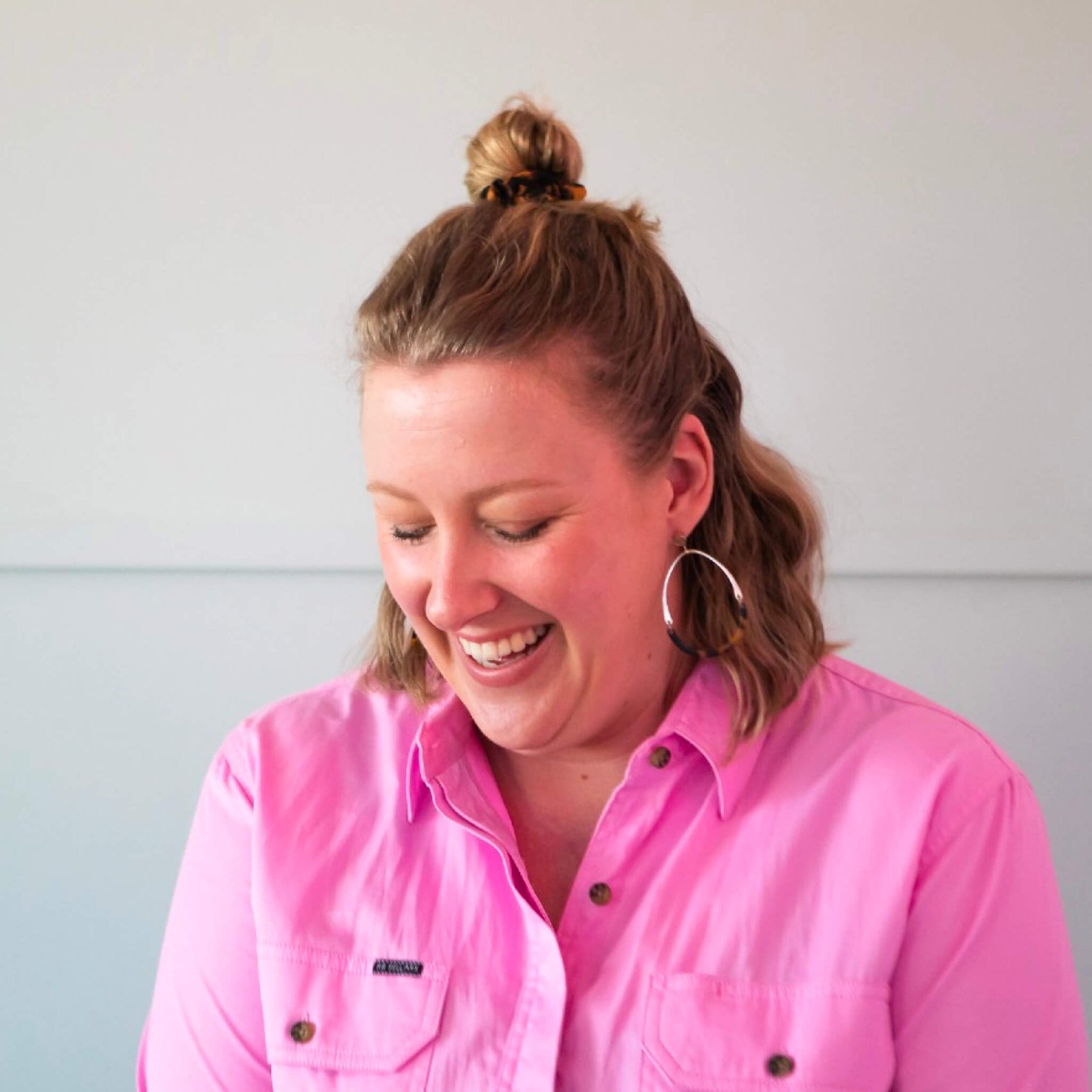 Brand design portfolio image featuring brand photography for Sarah Standford. Sarah wears a pink jumpsuit and laughs while looking down. 