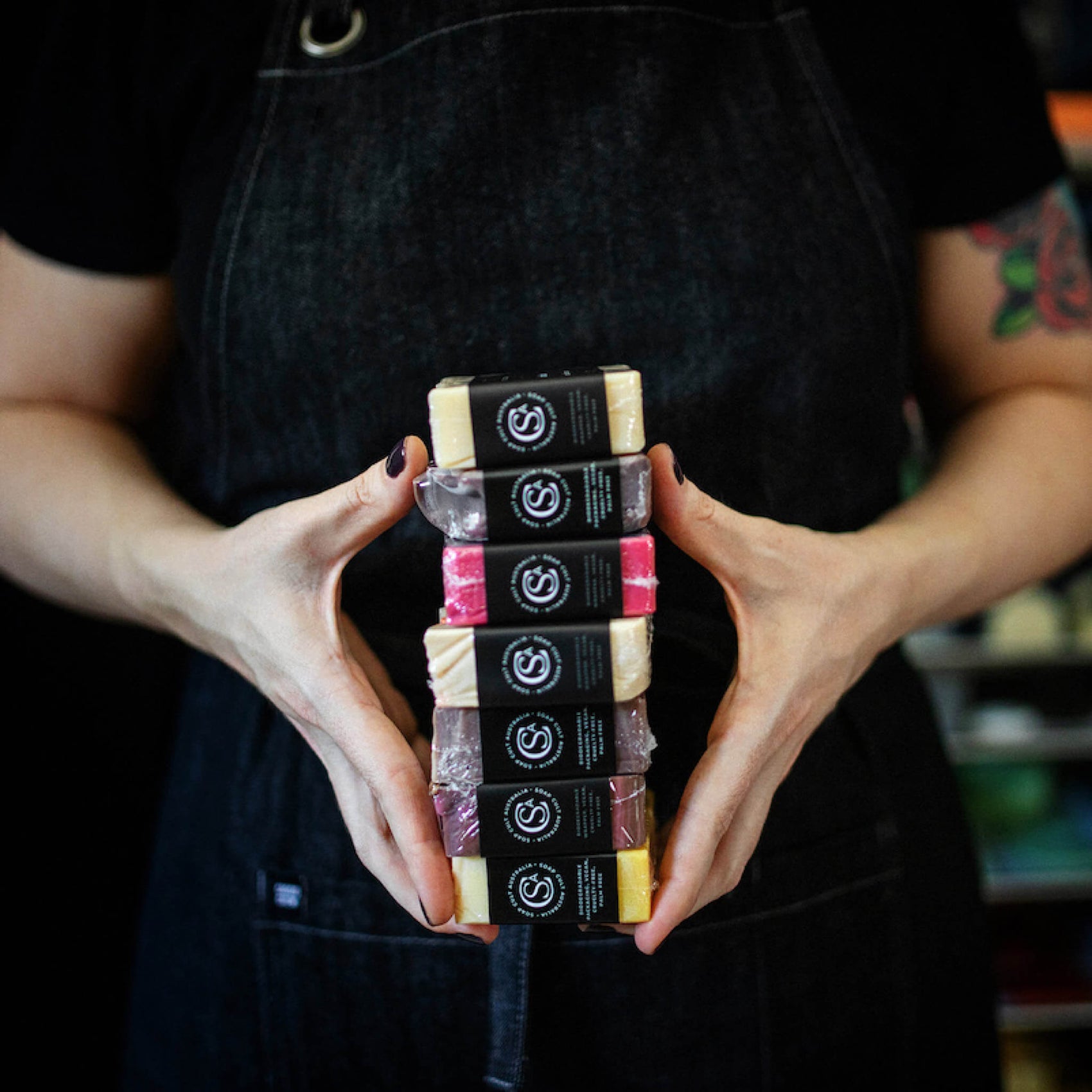Brand designer portfolio image of two hands holding Soap Cult Australia soaps. The brand monogram and key details are on the edge of the soap in white on a black label background. 