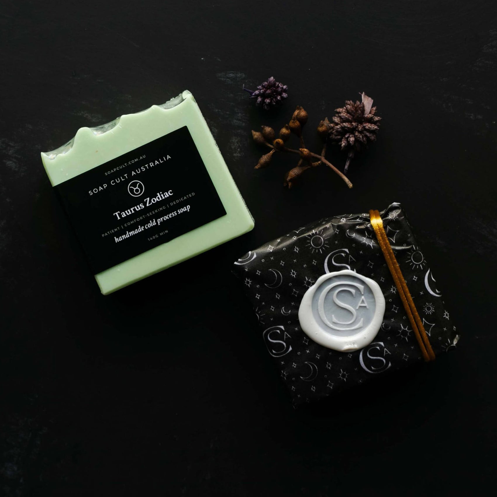 Soap brand identity case study image showing two Soap Cult Australia soaps in a black setting. One soap is mint green and showcases a minimal-style zodiac label while the other has a white wax seal and is wrapped in soap cult tissue paper. 