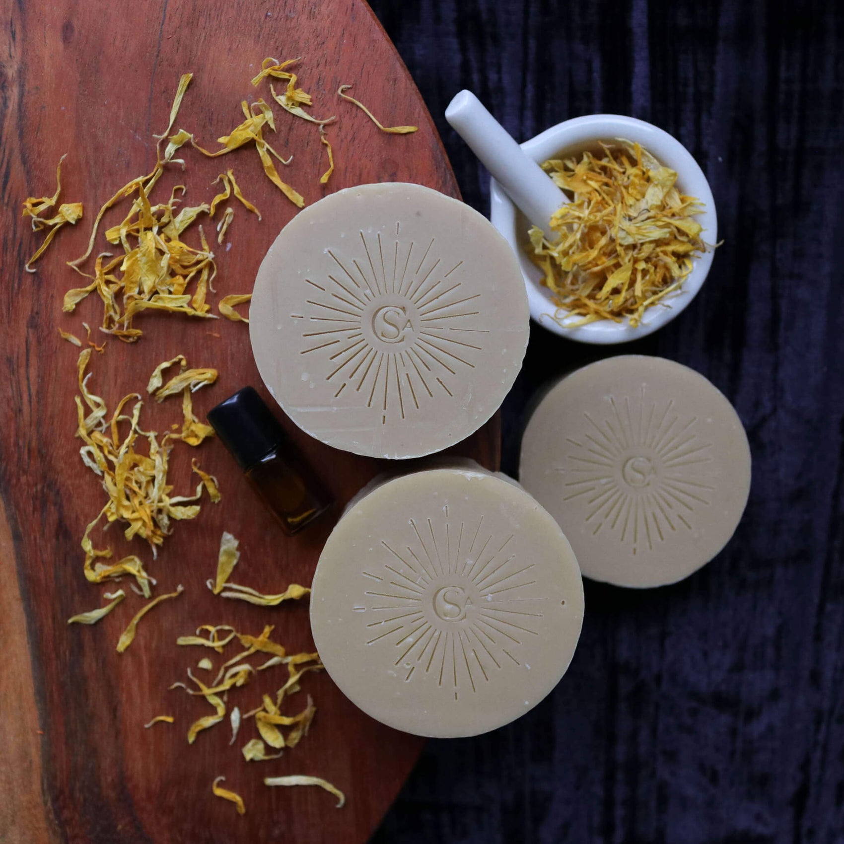 A skincare rebranding case study product image of Soap Cult Australia facial soaps on a wooden board. The soaps are stamped with the esoteric-inspired branding monogram, radiating lines coming out from the center. 