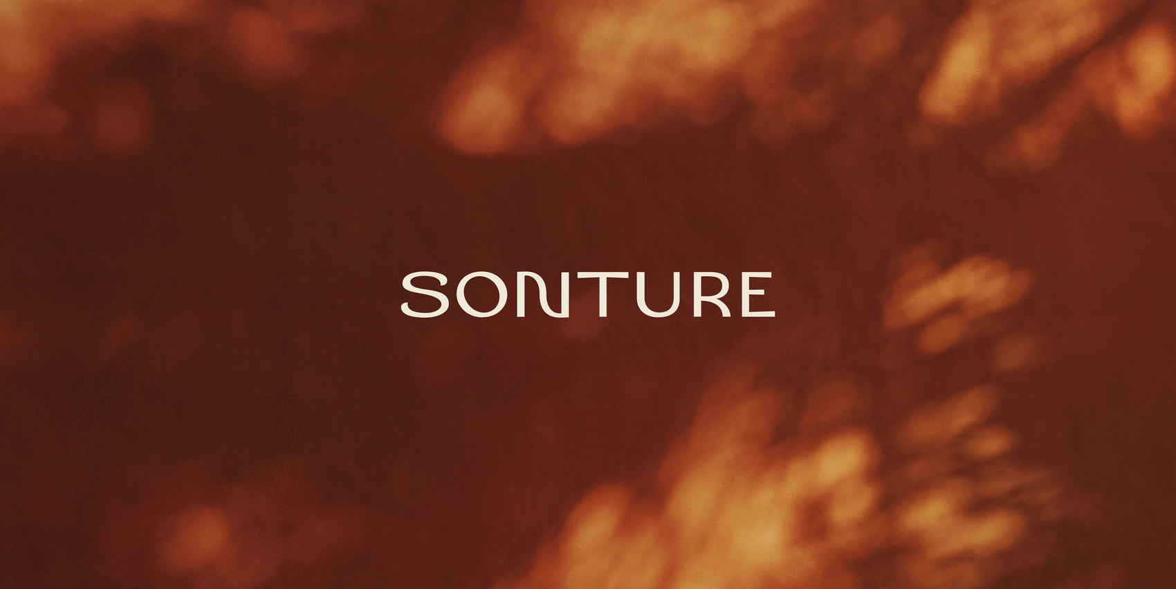 Skincare branding case study image of the Sonture logotype on a shadowy brown background. The minimal sans serif logo features a ‘N’ with a wave in it. 