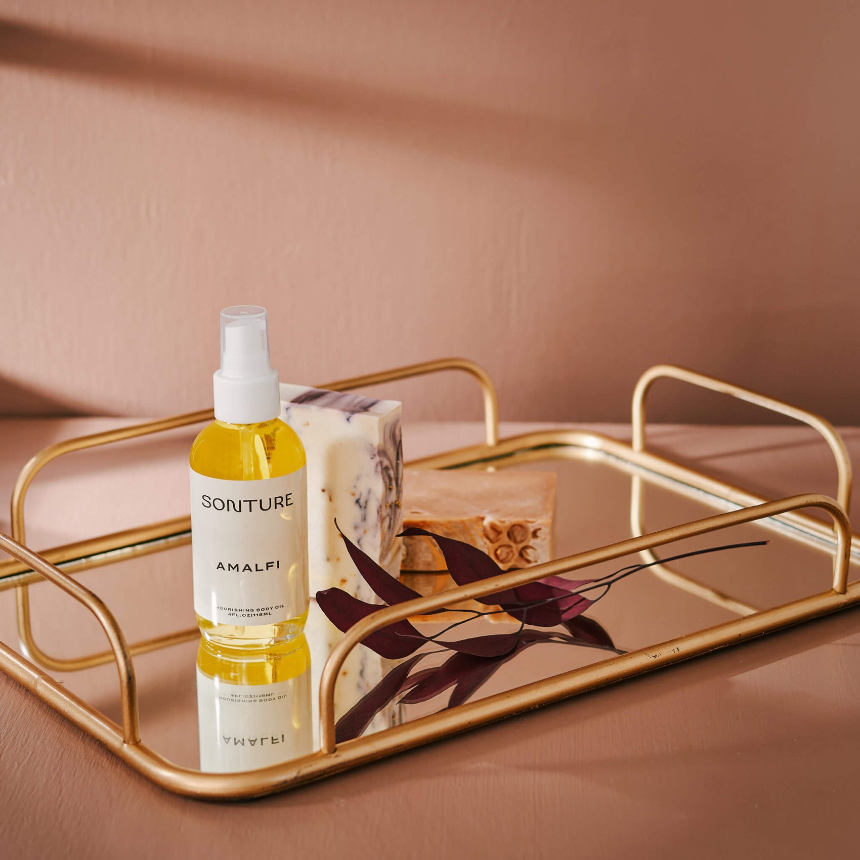 Soap brand design portfolio image of the Sonture body oil on a gold tray in an elegant setting. The very minimal label creates a minimal, high end feel. 