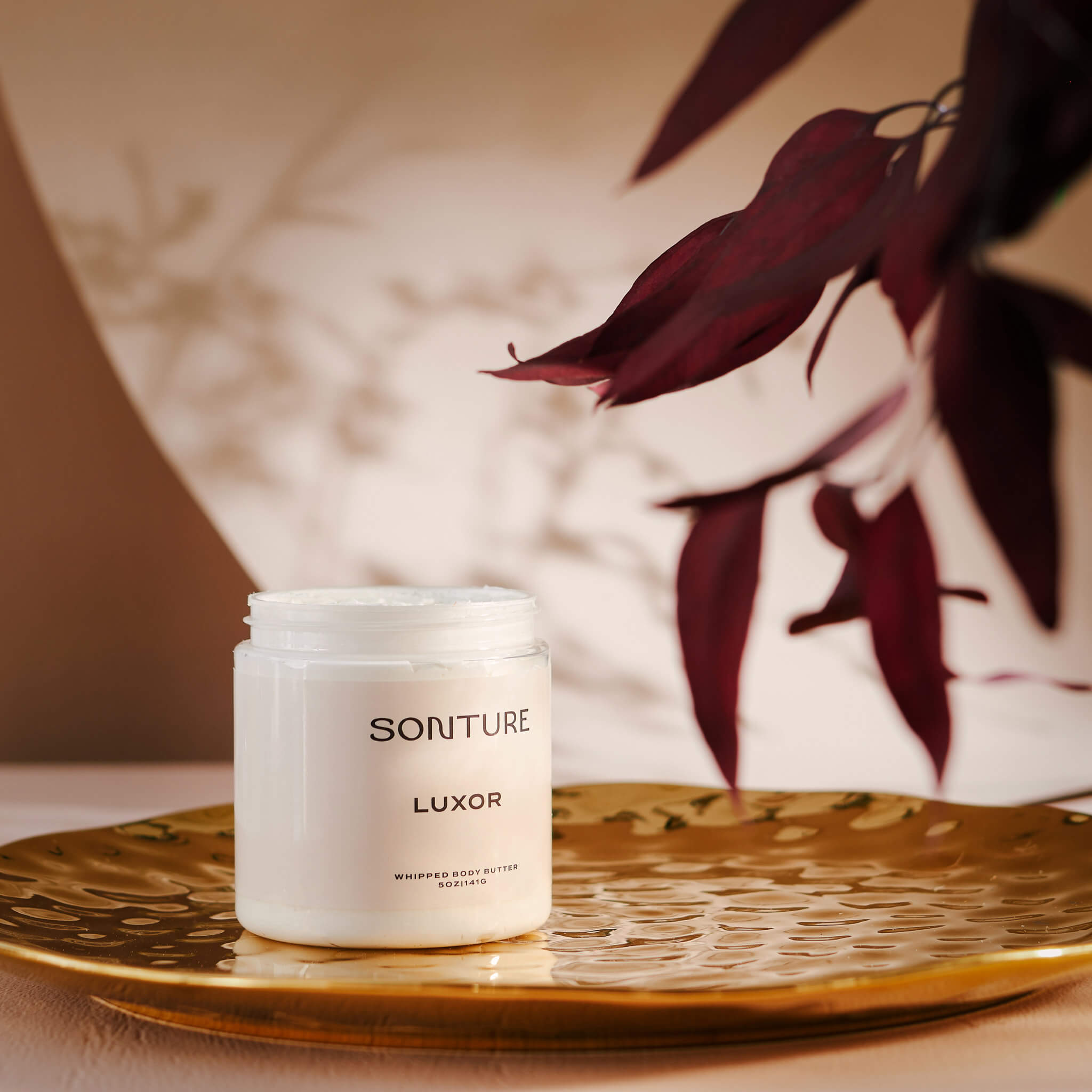 Soap brand design portfolio image of the Sonture body butter on a gold tray in an elegant setting. The very minimal label creates a minimal, high end feel. 