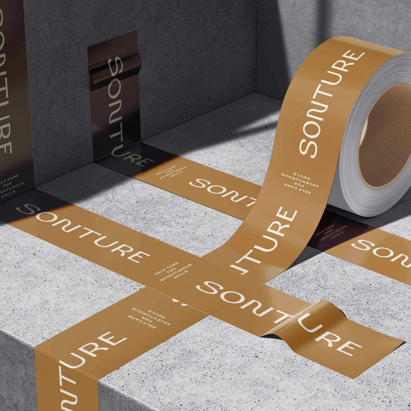 Skincare brand identity examples image of the Sonture custom packing tape in a brutalist concrete setting. The warm brown tape features the logo and taglines in white. 