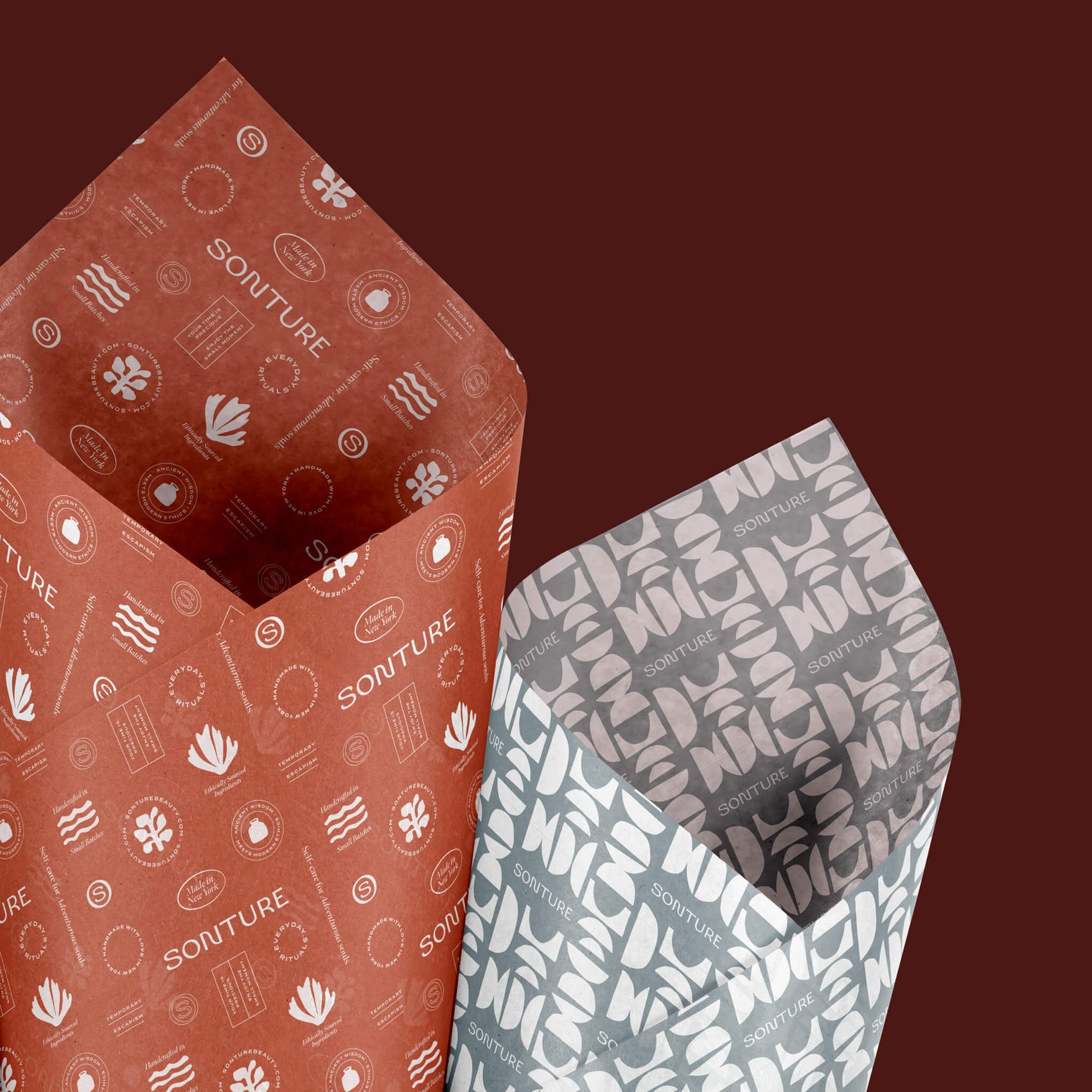 Rebranding case study images of the custom tissue paper design created for Sonture. On a brown background sits two designs- a rust coloured ones with white brand marks as well as a light blue one with white geometric shapes. 