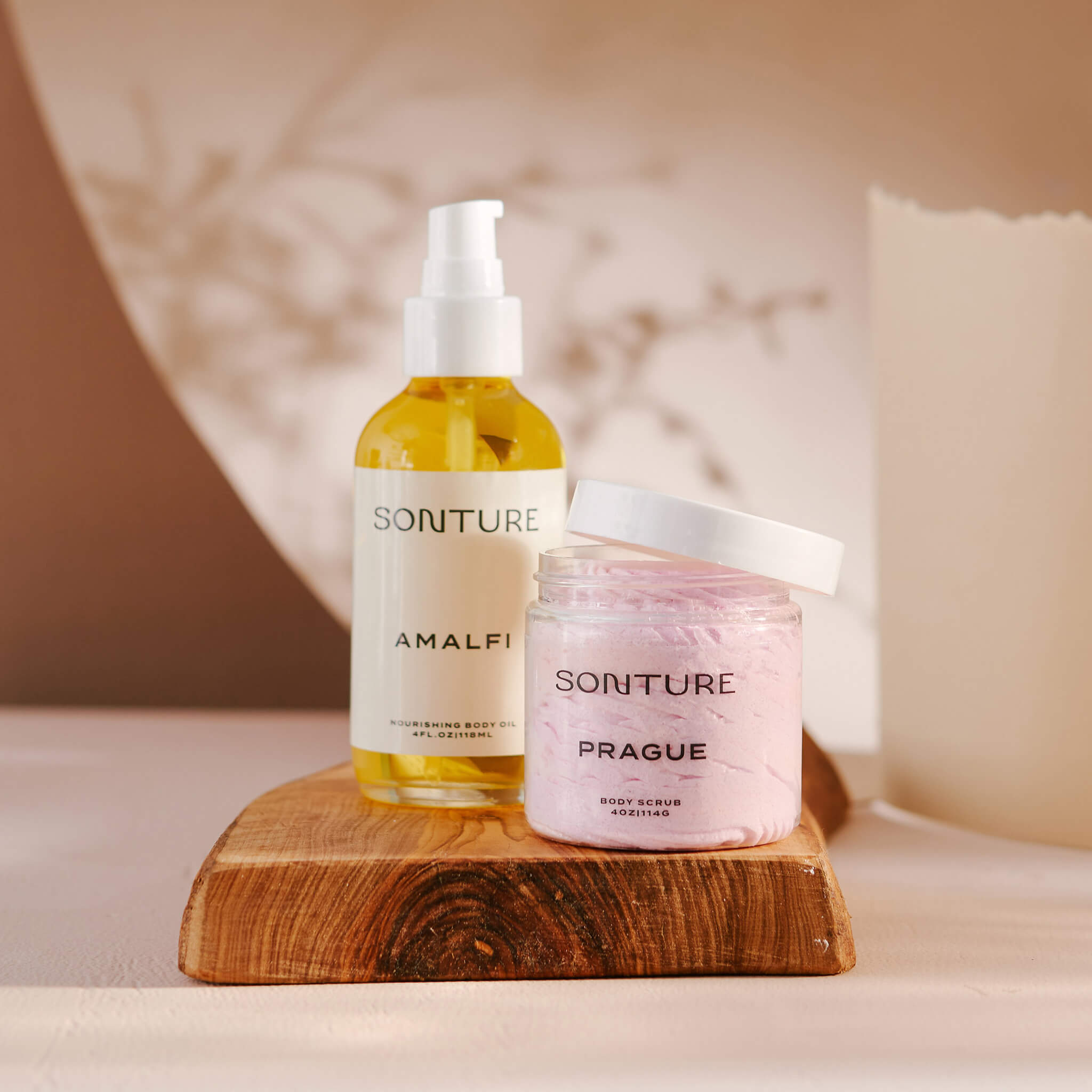 Soap brand designer portfolio image showcasing the Sonture skincare packaging design applied to a body oil and whipped body butter. The products feature minimal labels for a high end feel with the shadowy setting making for a high end image. 