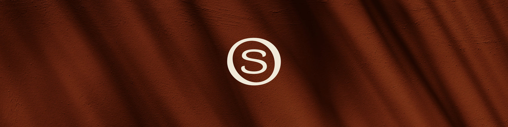 Candle brand designer portfolio image of the Sonture brand icon in cream on a shadowy brown coloured background. 