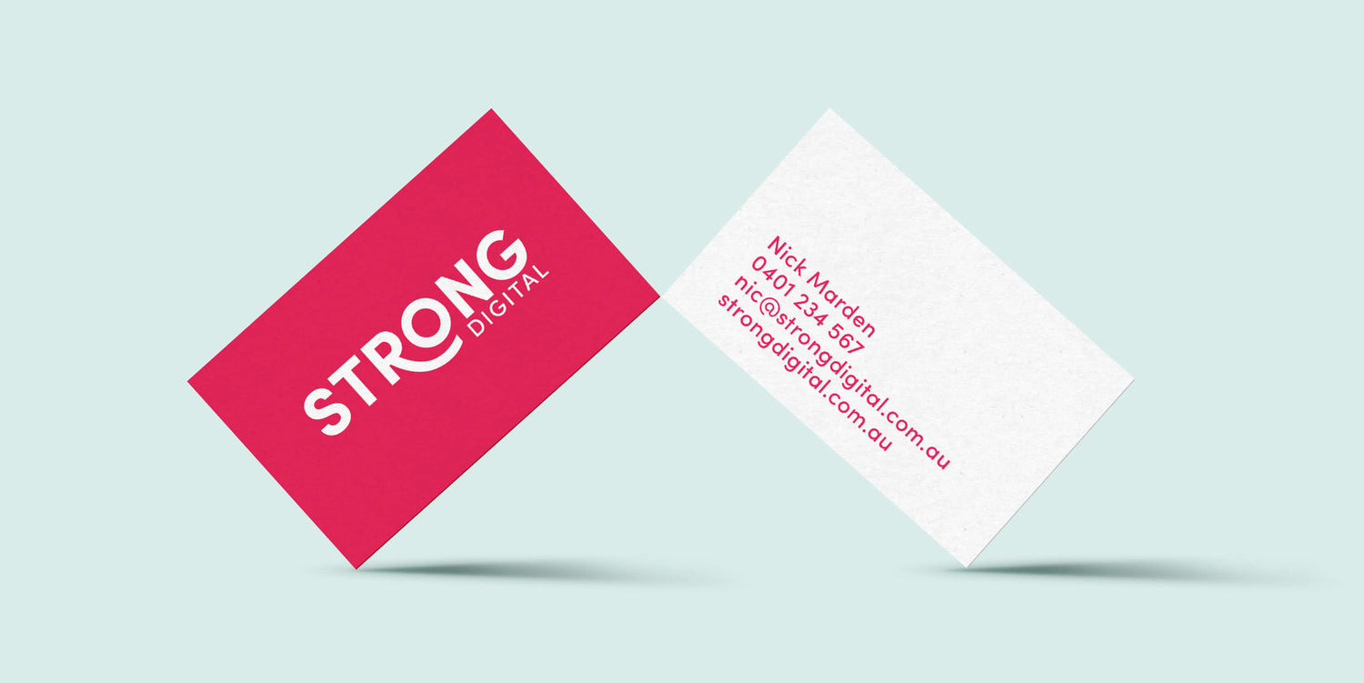 Brand design examples image of the Strong Digital agency business cards in a light blue background. The front is in a BRIGHT pink while the back card is white with contact details in pink.