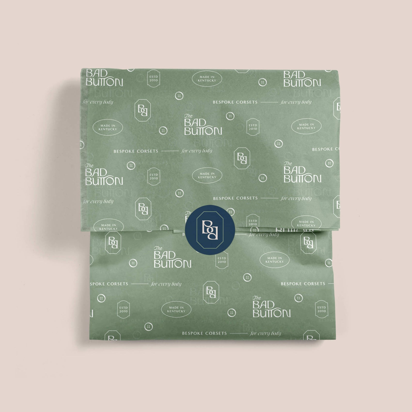 Fashion label brand Designer Portfolio image of The Bad Button custom tissue paper and brand sticker. The tissue paper design featured the brand marks in white on a mint coloured background, the blue brand seal sticker pulling it all together. 