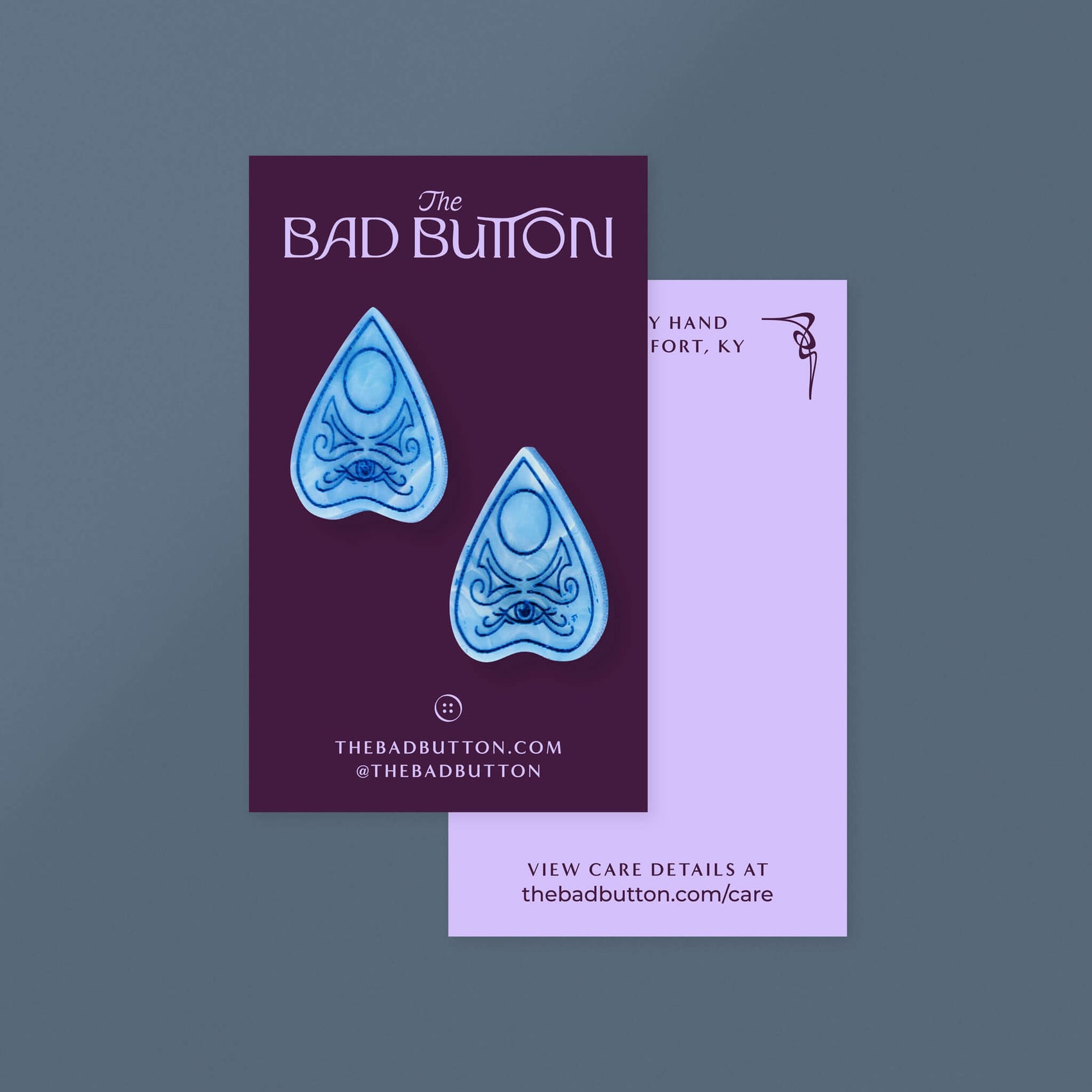 Brand design portfolio image showcases The Bad Button’s jewellery packaging design in the form of purple backing cards. The front features the brand logo, URL and social tags while the back features some of the brand illustrations as a frame as well as a link to care information.