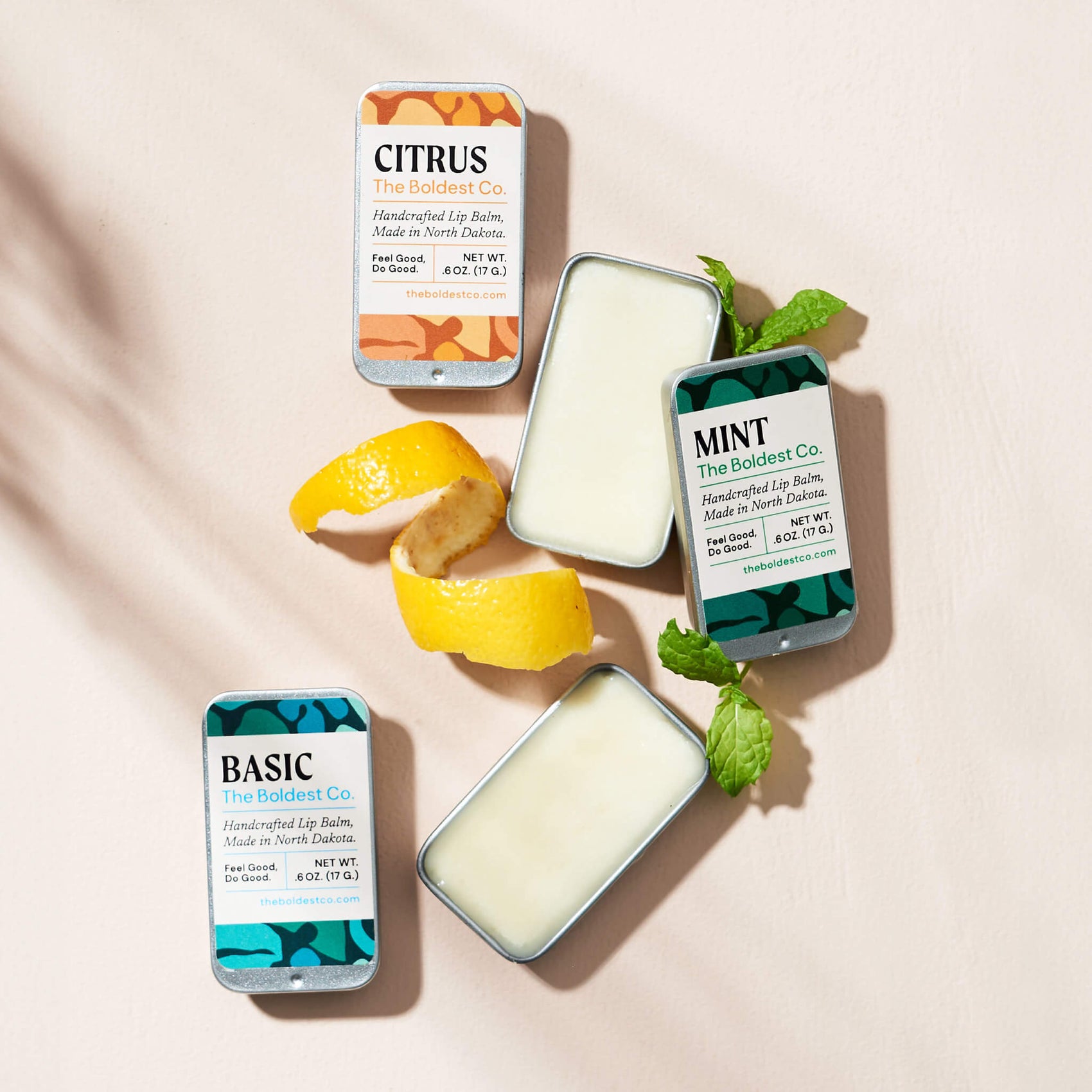 Soap brand design portfolio styled image of The Boldest Co’s lip-balms. The tin packaging features bright colours and mid-century inspired design and is surrounded by decorative lemon and mint garnishes. 