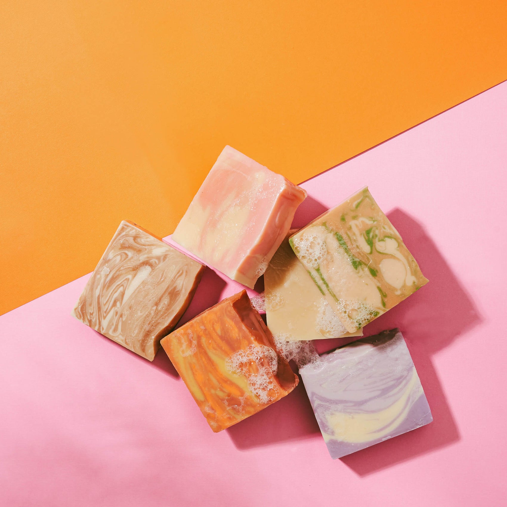 A stack of The Boldest Co’s soap bars on a pink/orange paper background 
