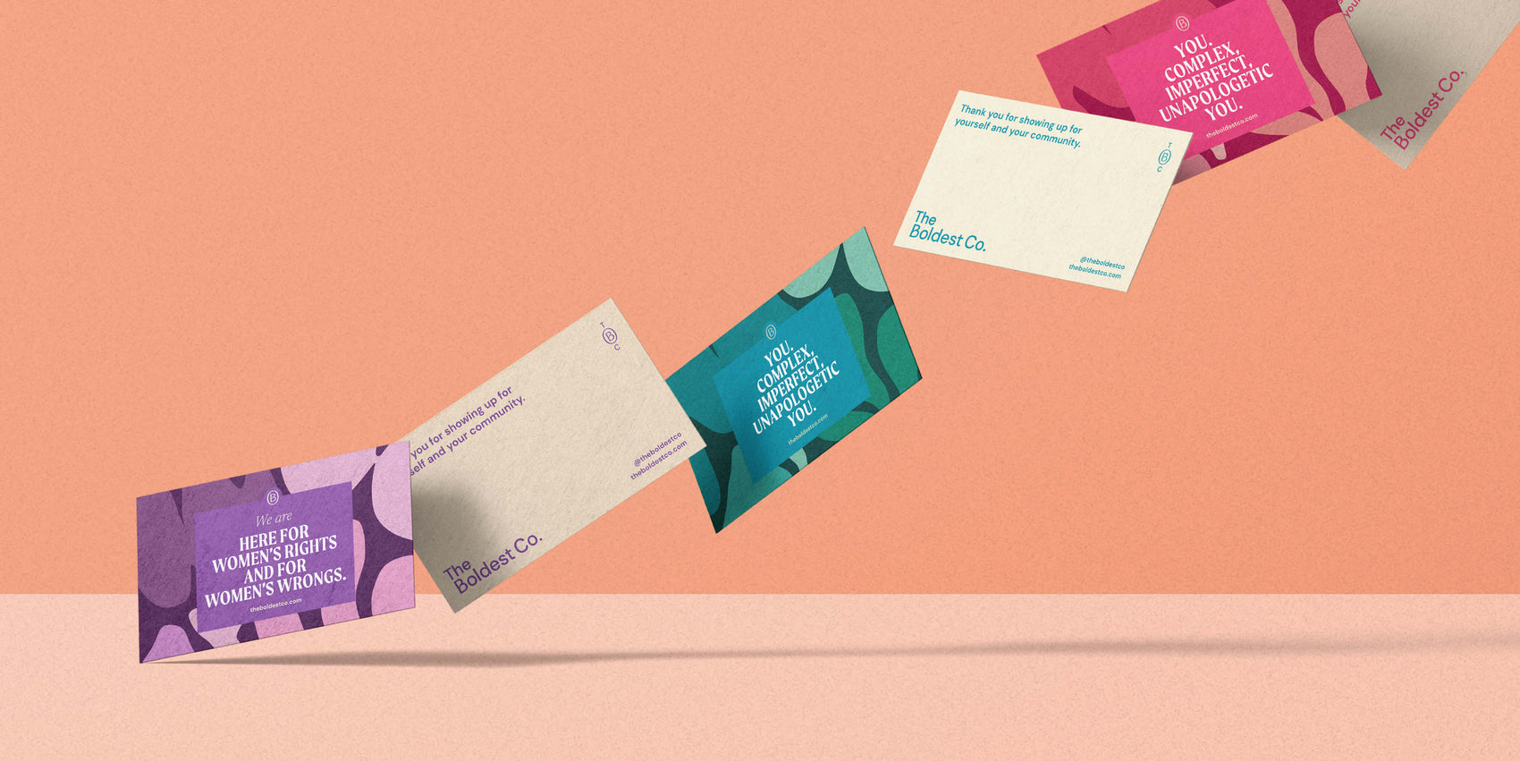 Brand design portfolio image of The Boldest Co’s range of thank you cards flying through a pink background. The front face shows different brand messaging surrounded by the brand pattern with the backs using single colour printing and space for a message.