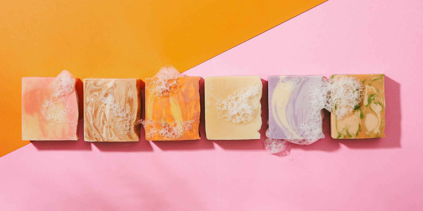 A line up of personal care Brand The Boldest Co’s soap bars on a pink/orange paper background as part of the brand identity case study. 