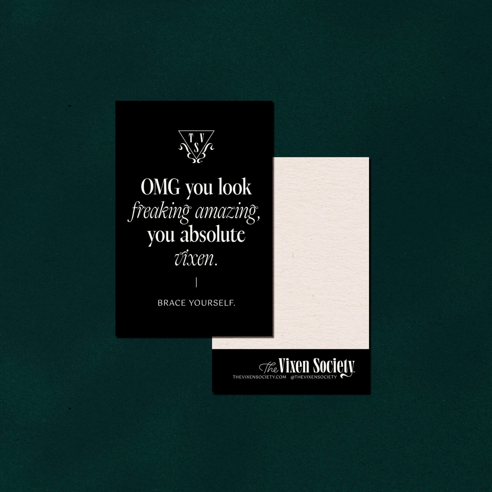 On a deep green background sits the front and back view of The Vixen Society thank you cards. The front features the brand icon and URL with copy that says "OMG you look freaking amazing you absolute vixen' in an elegant serif typeface. The back features another brand logo and social details as well as white space for a handwritten note.