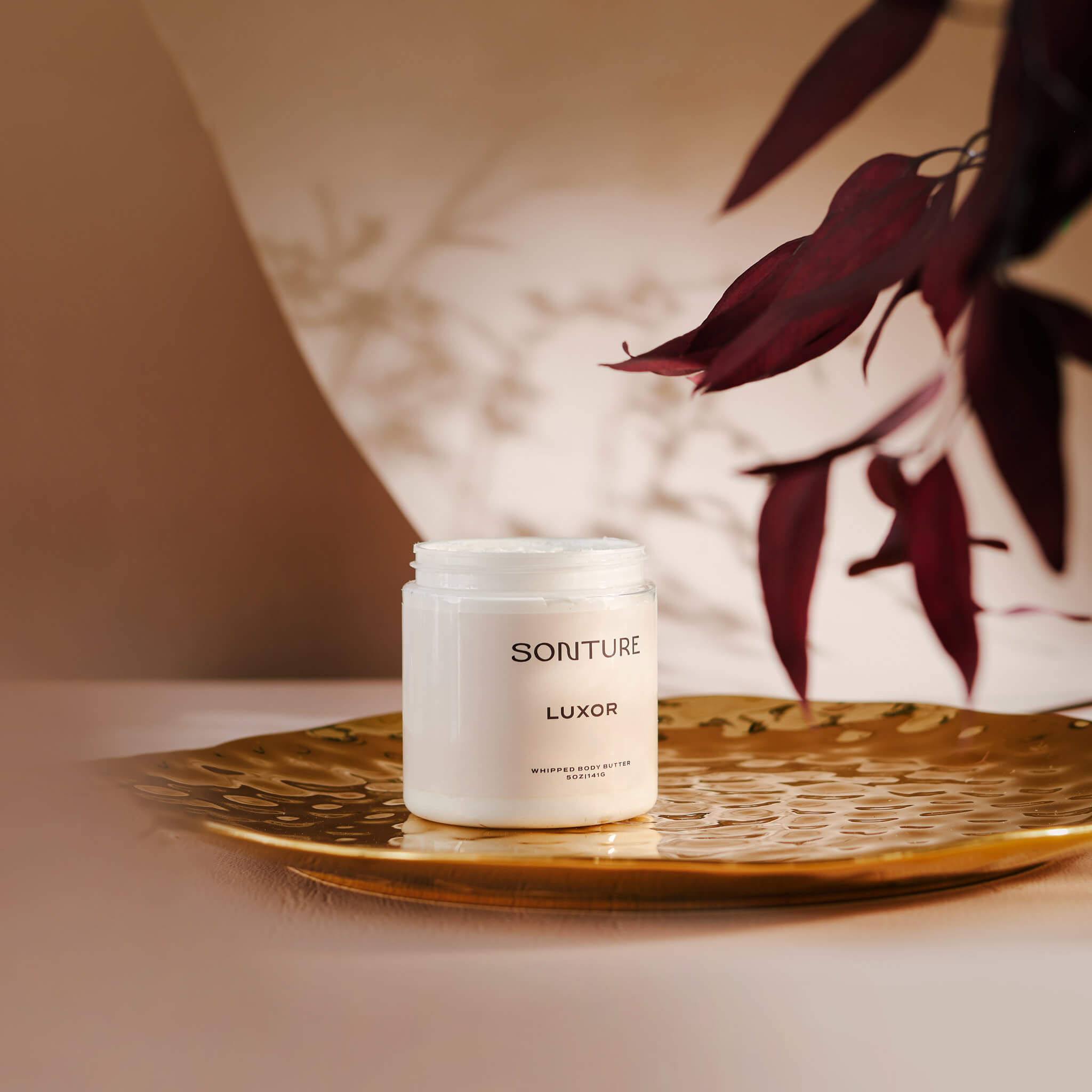 Soap brand design portfolio image of the Sonture body butter on a gold tray in an elegant setting. The very minimal label creates a minimal, high end feel. 